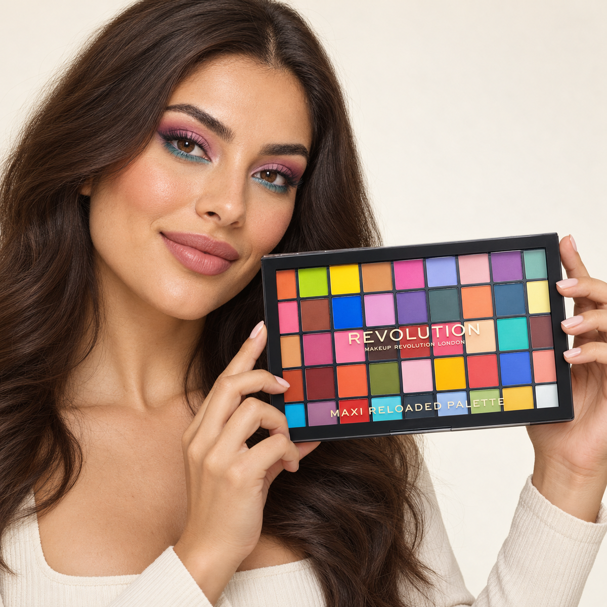 Model holding Revolution Maxi Reloaded Monster Mattes Palette with pink and teal eye makeup