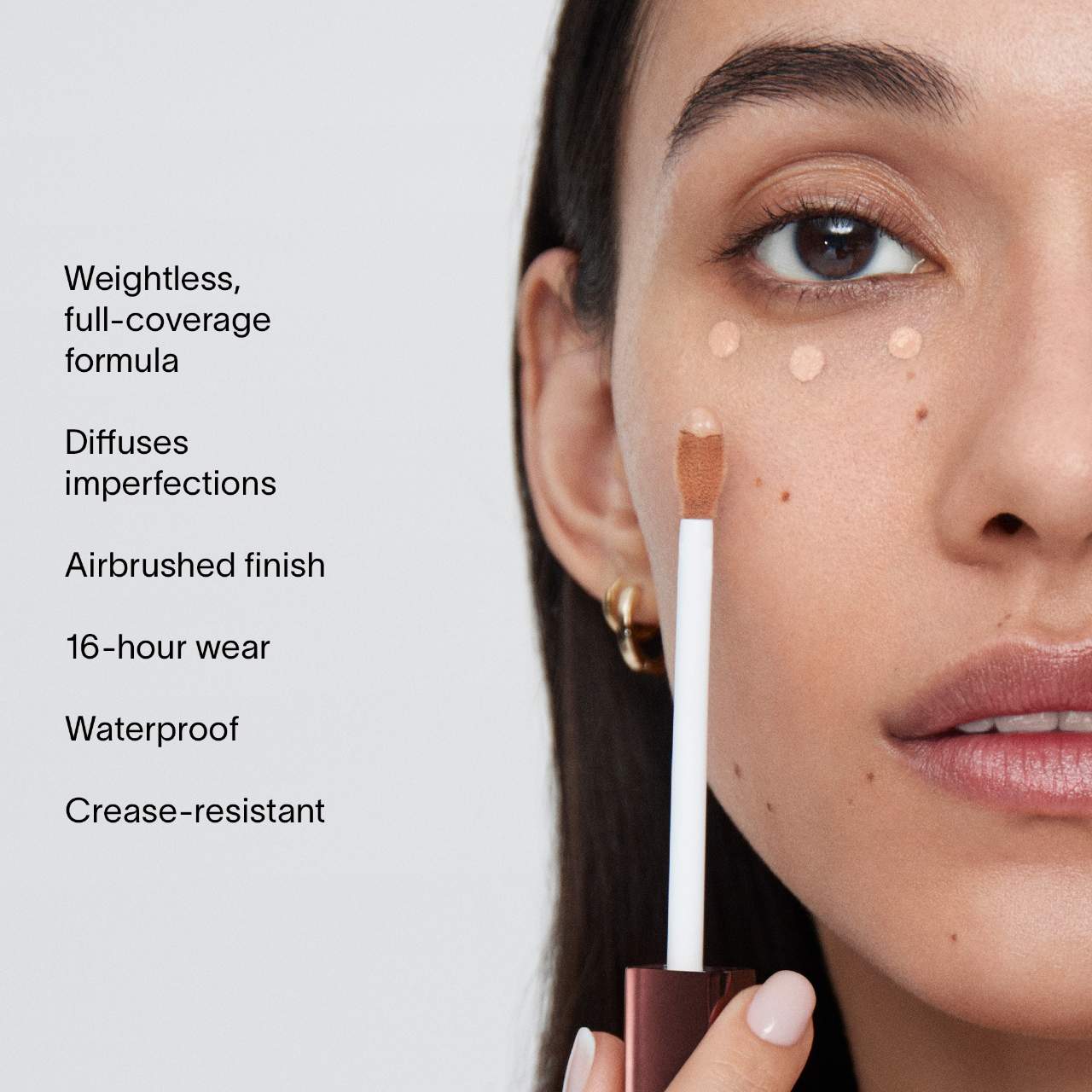 Model applying Hourglass Vanish Airbrush Concealer under eyes with benefits including full coverage, waterproof wear, and crease resistance