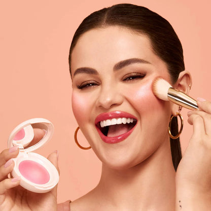 Model applying Rare Beauty Soft Pinch Luminous Powder Blush on cheeks