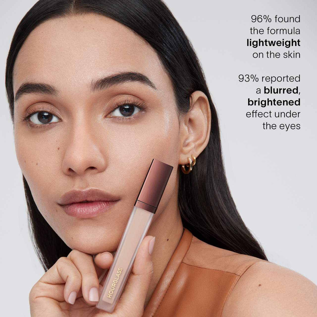 Model holding Hourglass Vanish Airbrush Concealer with text highlighting lightweight feel and brightening under-eye effect