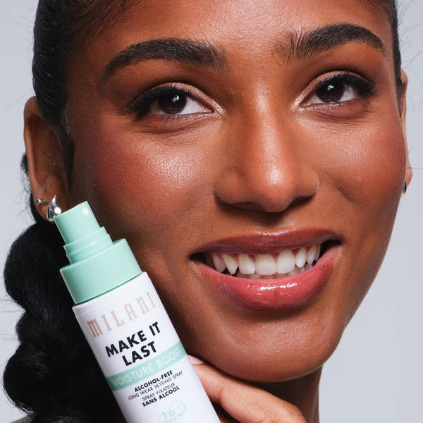 Model holding Milani Make It Last Moisture Boost Setting Spray beside her hydrated makeup look.