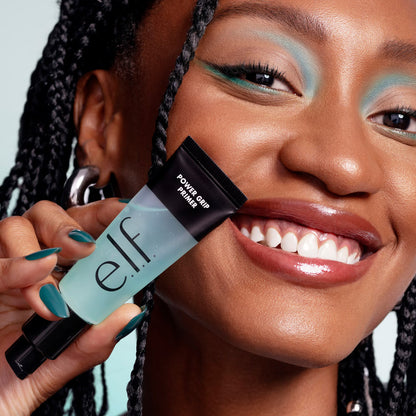 Woman holding e.l.f. Power Grip Primer showing hydrated glowing skin