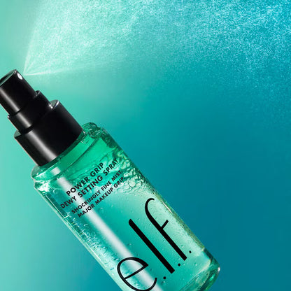 e.l.f. Power Grip Dewy Setting Spray releasing fine mist on teal background